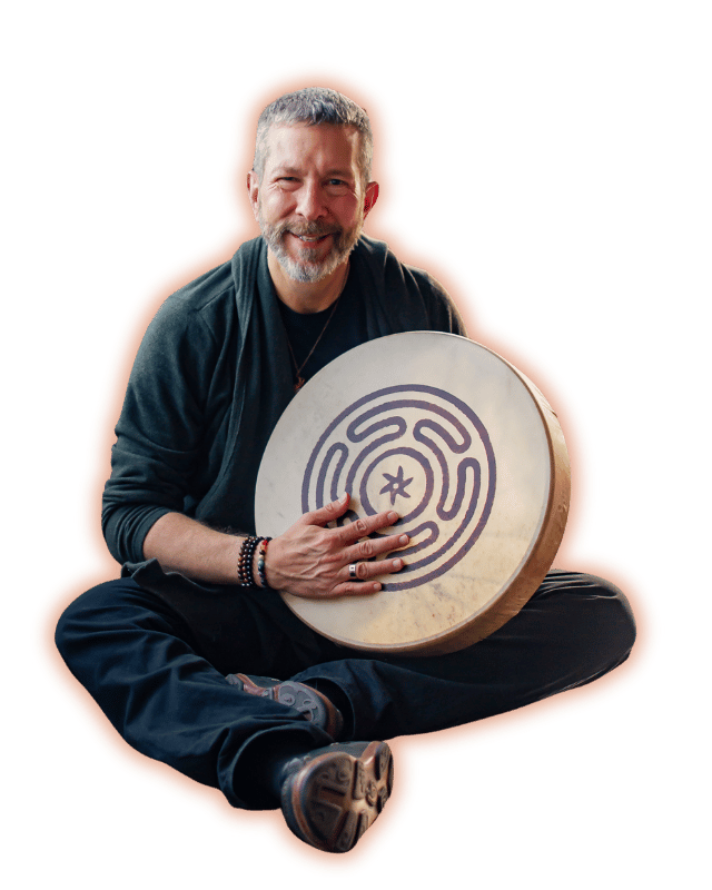 Julian Crosson-Hill sitting cross legged and holding a frame drum